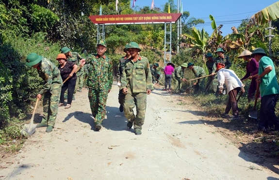 Đại úy Đinh Văn Tuấn (người đội mũ mềm) và chiến sĩ giúp dân bản sửa đường giao thông.